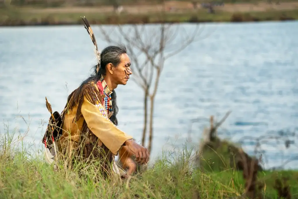 Indigenous man crouching by that water